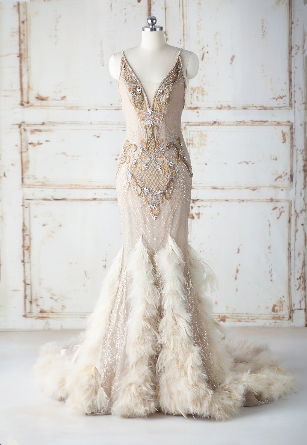 Tesia Bridal Gown cream ostritch feather adorned mermaid gown with gold glitter layer and hand beaded gold seed beads and rhinestones. Features cubic zirconium straps and corset back closure.