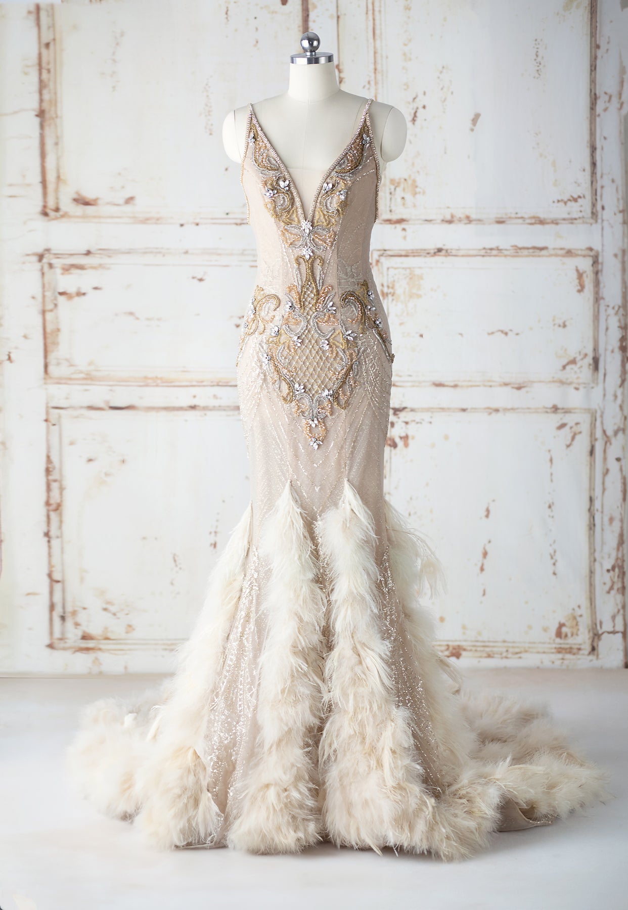Tesia Bridal Gown cream ostritch feather adorned mermaid gown with gold glitter layer and hand beaded gold seed beads and rhinestones. Features cubic zirconium straps and corset back closure.